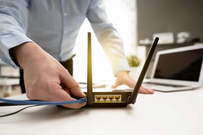 Ein Mann steckt ein Kabel in seinen Router.