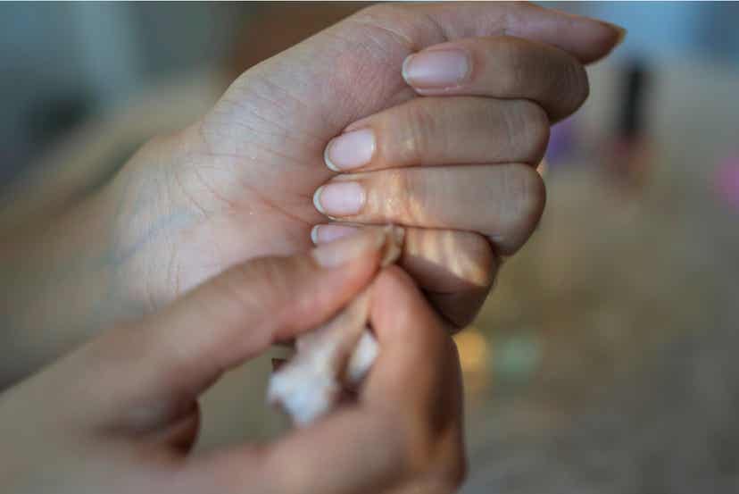 A woman rubbing paper towel over her fingernails.