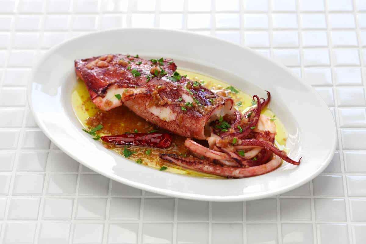 Gekochter Tintenfisch auf einem Teller mit Kräutern und Olivenöl.