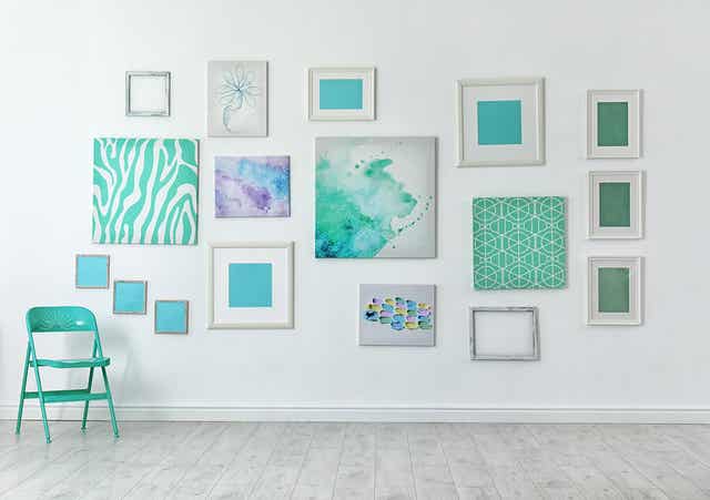 An arrangement of teal-colored artwork on a wall.
