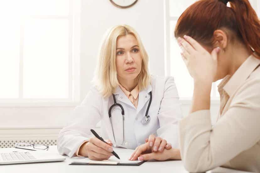 A woman who's looing upset as she talks with her doctor.
