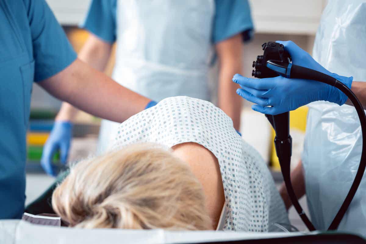 person lying down on their side in hospital gown and bed with doctors surrounding them