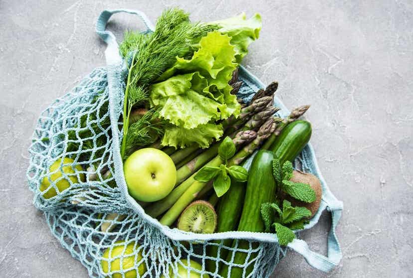 A bad full of green fruits and vegetables.