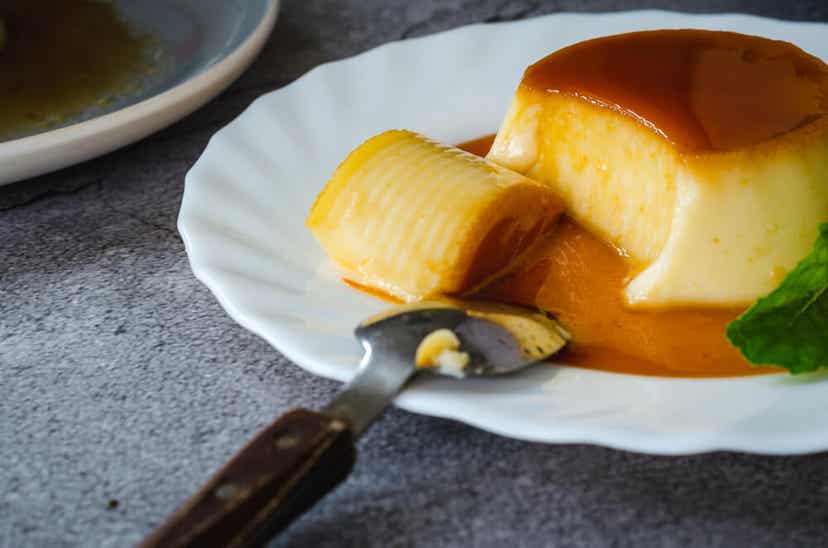 Eine teilweise gegessene Portion Flan auf einem Dessertteller.
