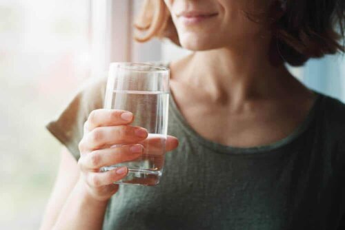 En kvinde, der drikker et glas vand, drikker danskvand hver dag