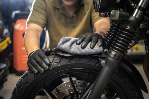 5 Tipps für die Motorradwartung zu Hause - Jemand, der einen Reifen reinigt.
