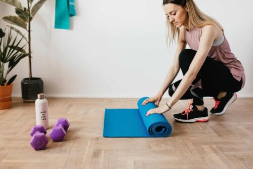 Yoga matını yuvarlayan bir kadın.