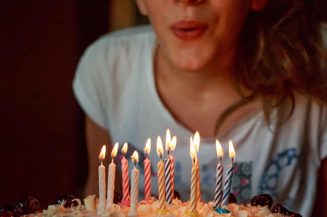 Μια γυναίκα που σβήνει τα κεριά σε μια τούρτα.