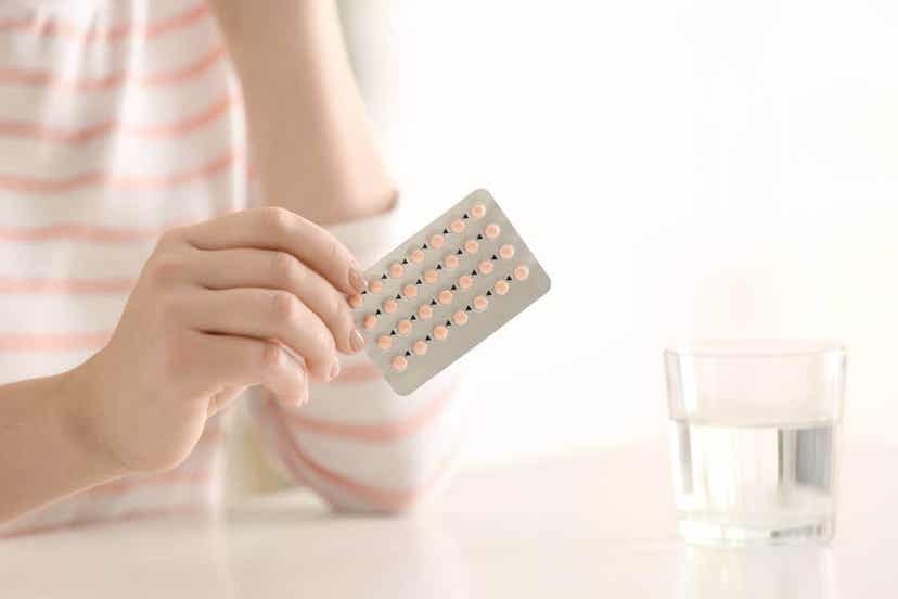A woman holding a blister pack of birth control pills.