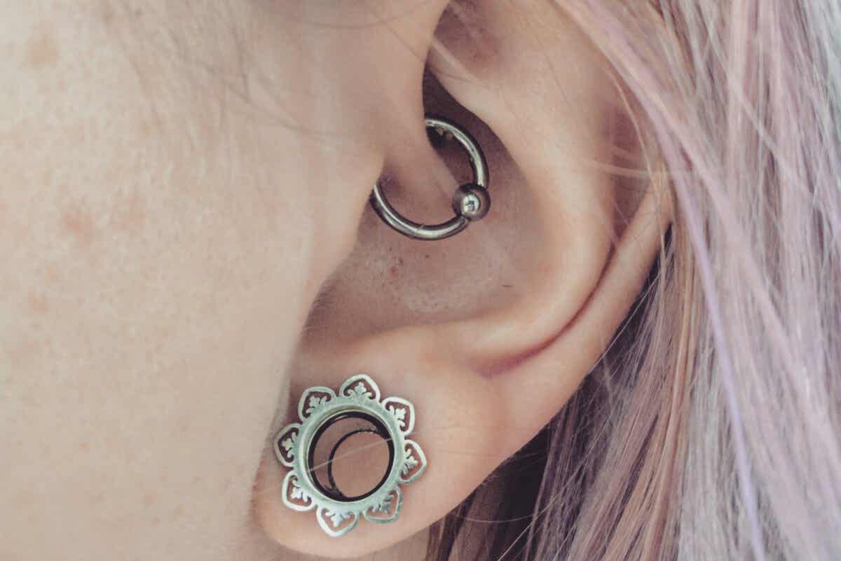 En kvinne med 2 forskjellige typer piercinger i øret.