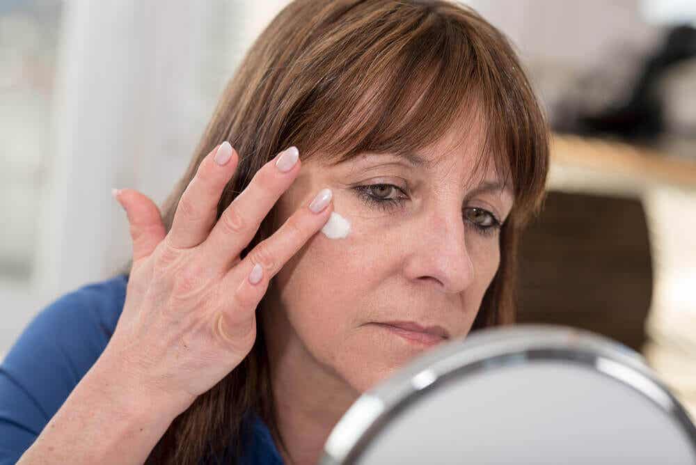 A woman applying cream on her face.