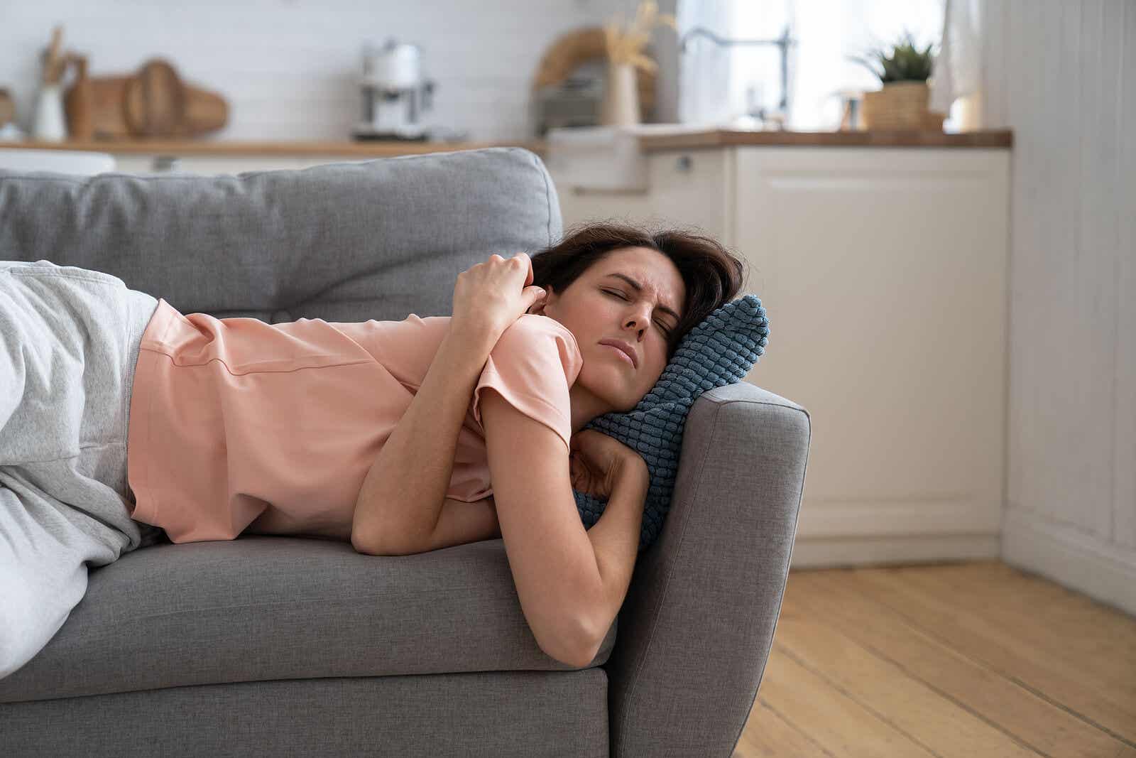 A woman taking a nap on the couch, looking uncomfortable.