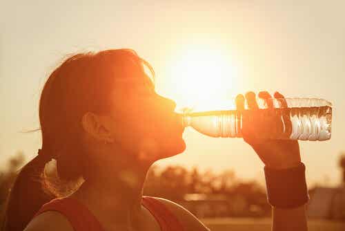 En kvinne som drikker vann fra en plastflaske på en varm dag.