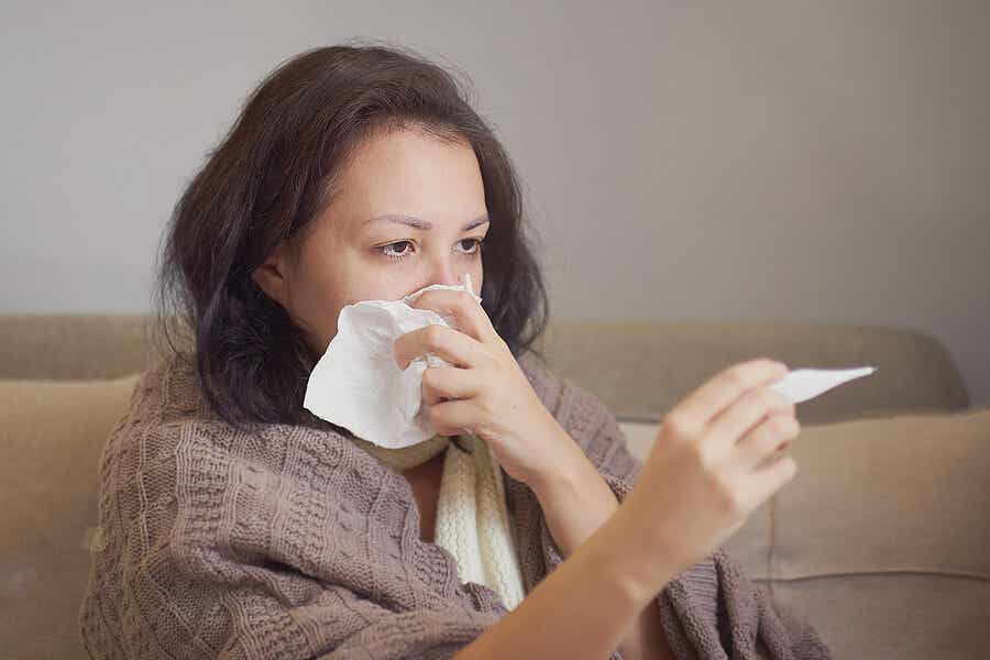 A woman with a runny nose taking her temperature.