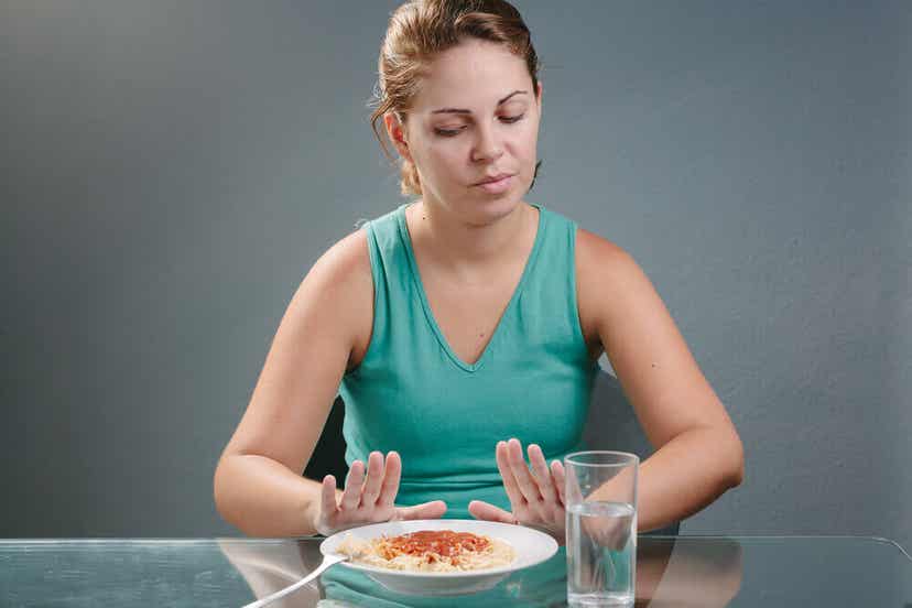 Ungewollter Gewichtsverlust - eine Frau schiebt eine Pasta von sich weg.
