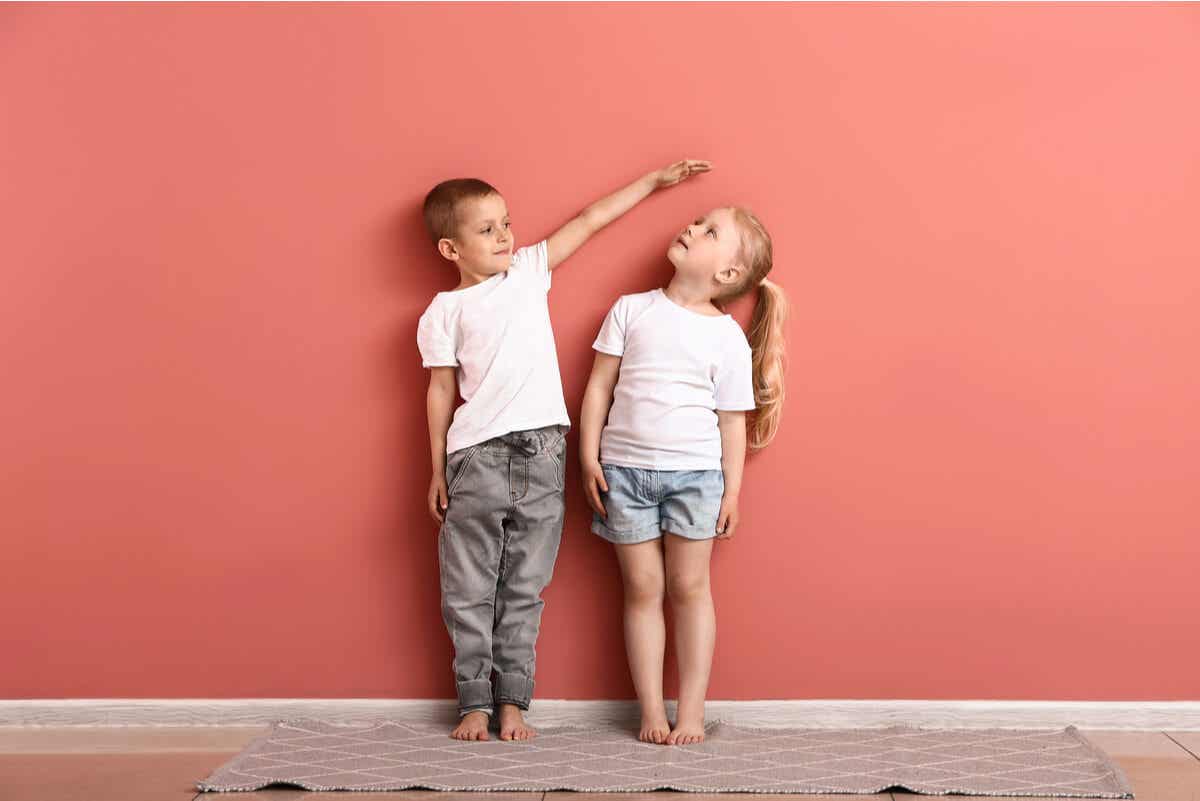 gutt og jente foran en rosa vegg som roter rundt og leker