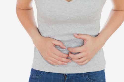 En kvinne med hendene over magen fordi hun føler seg kvalm.