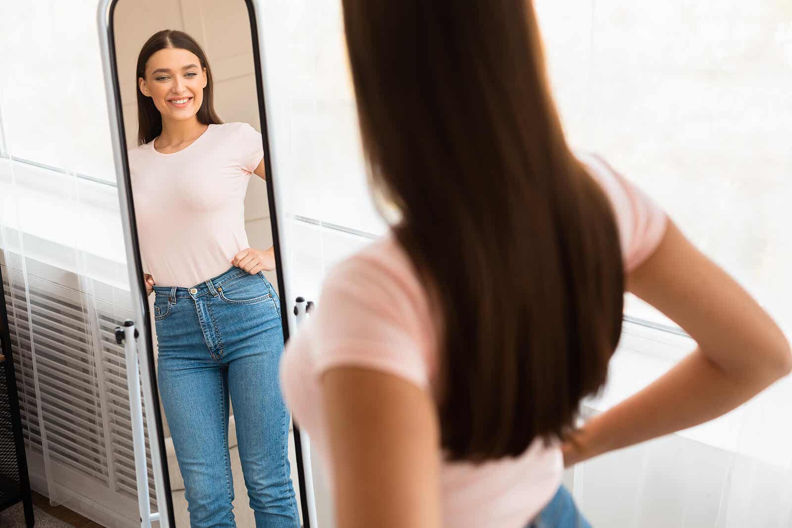 En smilende jente mens hun ser seg selv i speilet.