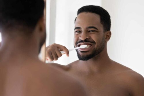 mann foran speilet smiler og pusser tennene