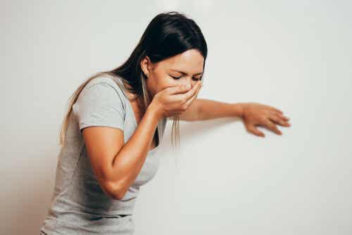 A woman covering her mouth with her hand because she's feeling nauseous.