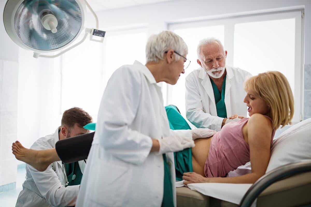 En gravid kvinne som blir besøkt av leger.