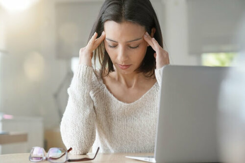 Kvinde ved computer tager sig til hovedet
