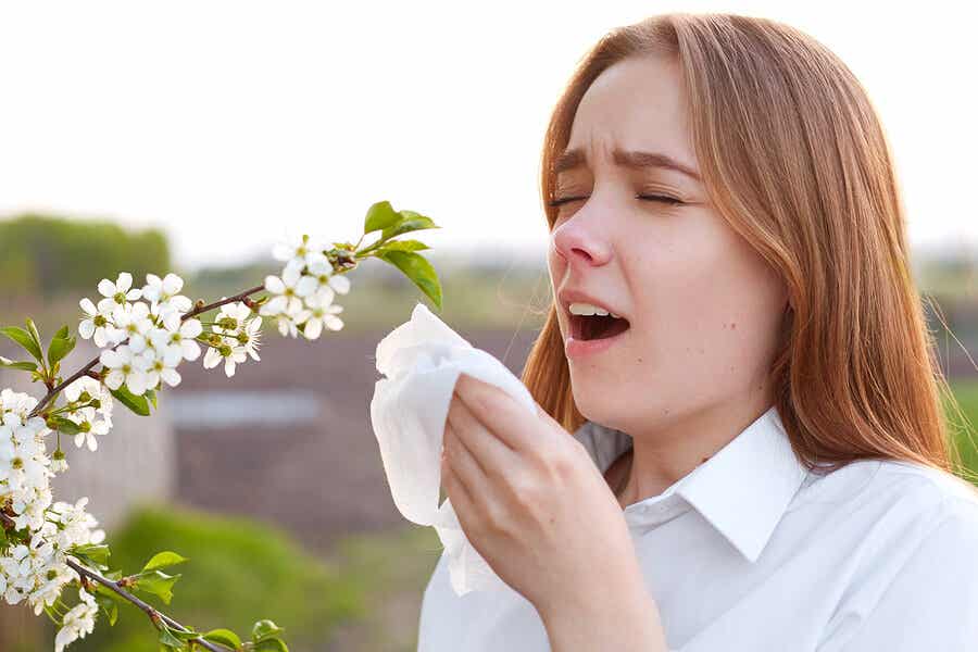 Una niña a punto de estornudar cerca de una flor.