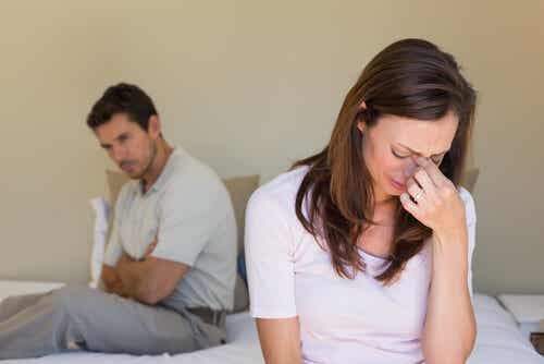 Angst beim Sex -weinende Frau und Mann mit verschränkten Armen auf einem Bett