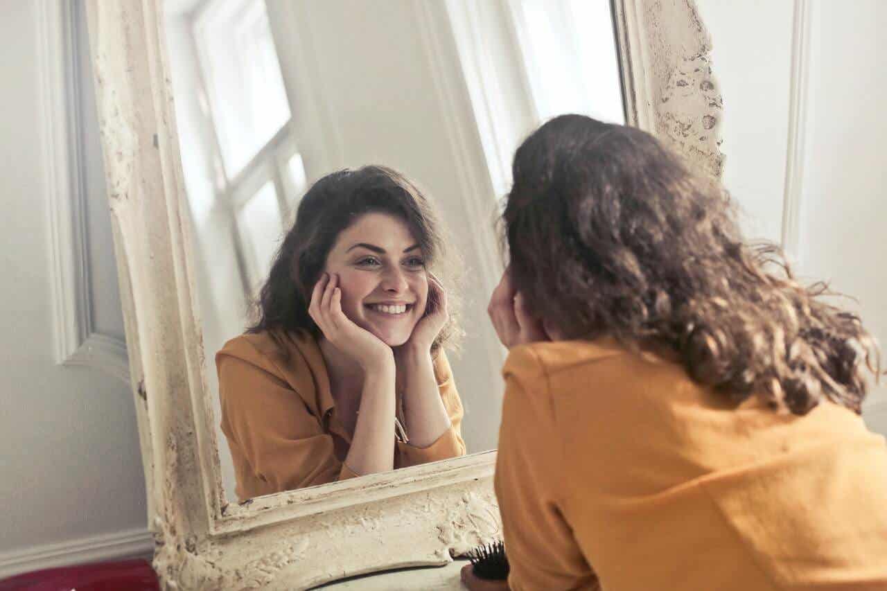 En kvinne som smiler mens hun ser seg i speilet.