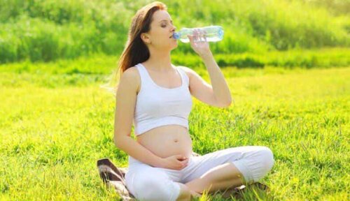 Μια έγκυος γυναίκα που πίνει νερό.