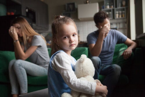 Trist pige med frustrerede forældre i baggrunden