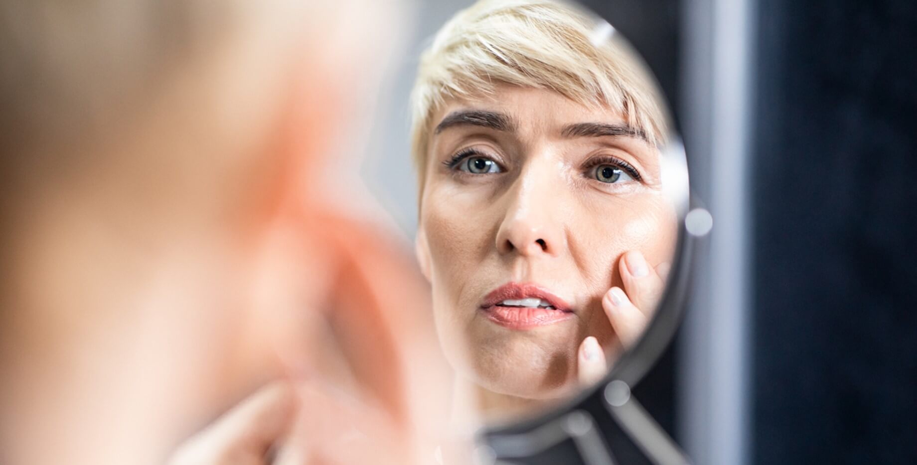 Vrouw bekijkt haar gezicht in een spiegel