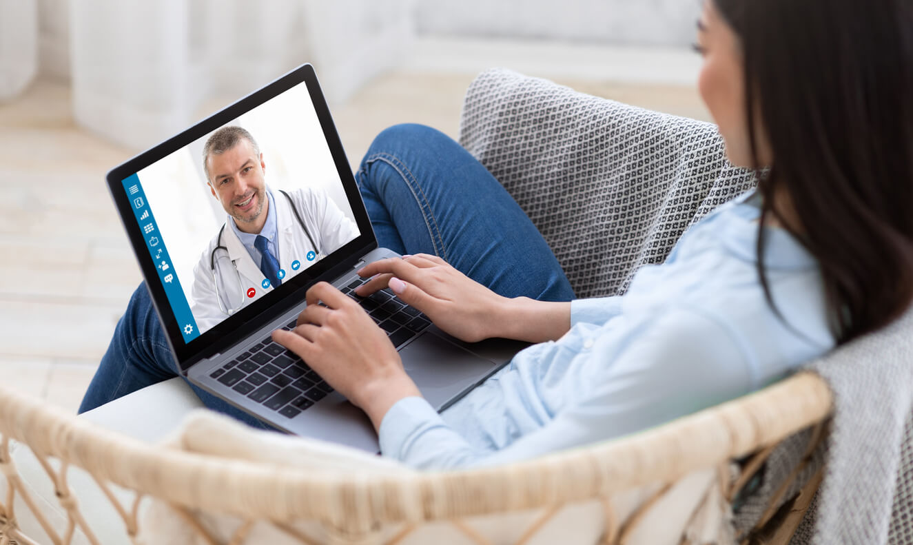 Telemedicine concept. Young lady consulting her doctor on laptop computer, using webcam from home, panorama. Millennial woman communicating with her health practitioner on internet